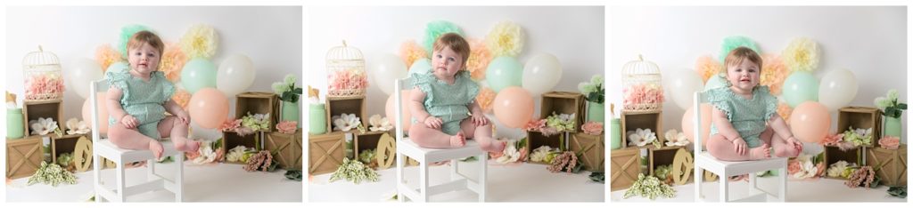 One year old girl sitting on while chair with peach and mint decorations