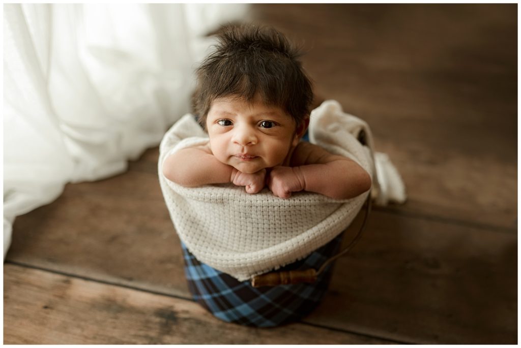 newborn with lots of hair in bucket pose 