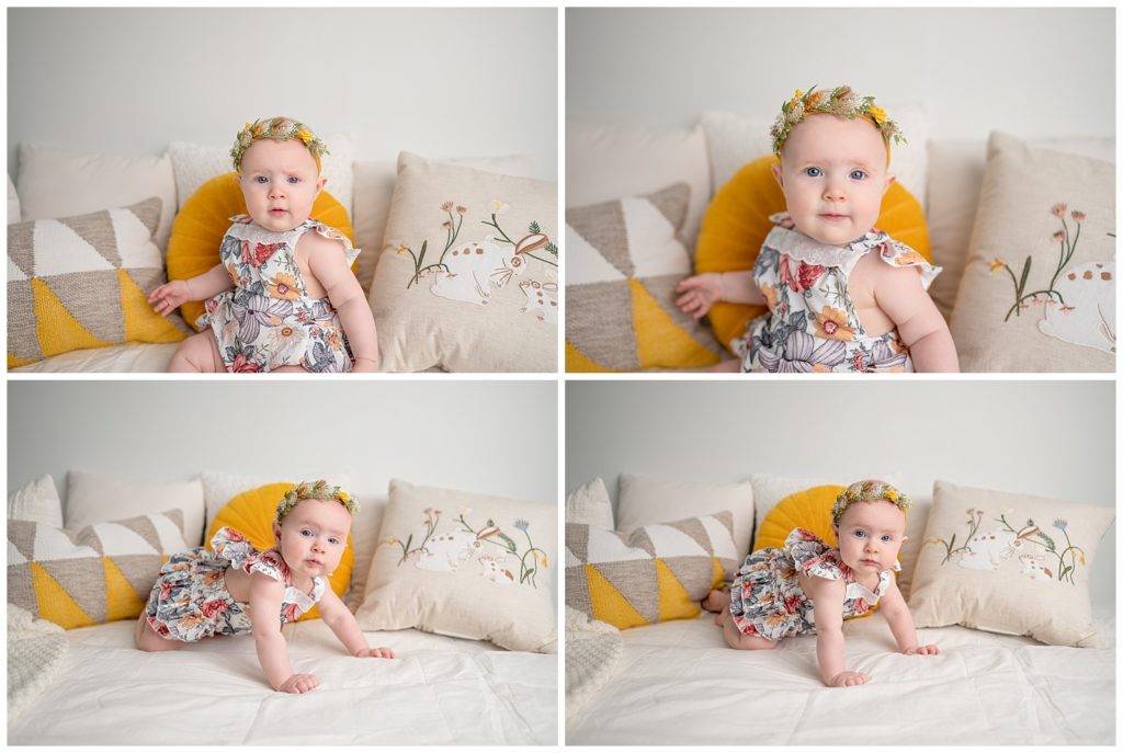 baby girl sitting on bed in floral romper